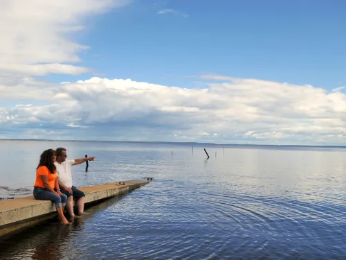 A couple sits on the dock by a lake in Plamondon Lac La Biche