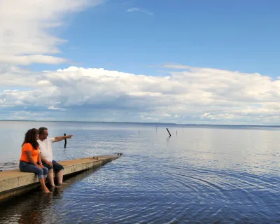 A couple sits on the dock by a lake in Plamondon Lac La Biche