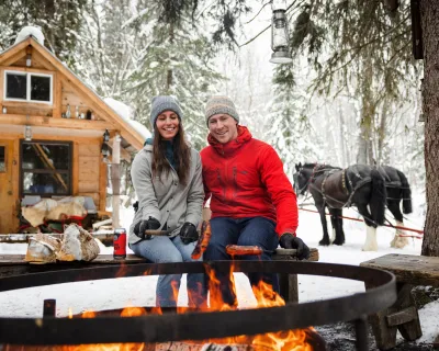 Couple enjoying a fire during a sleigh ride at B&T Adventures in Smithers BC