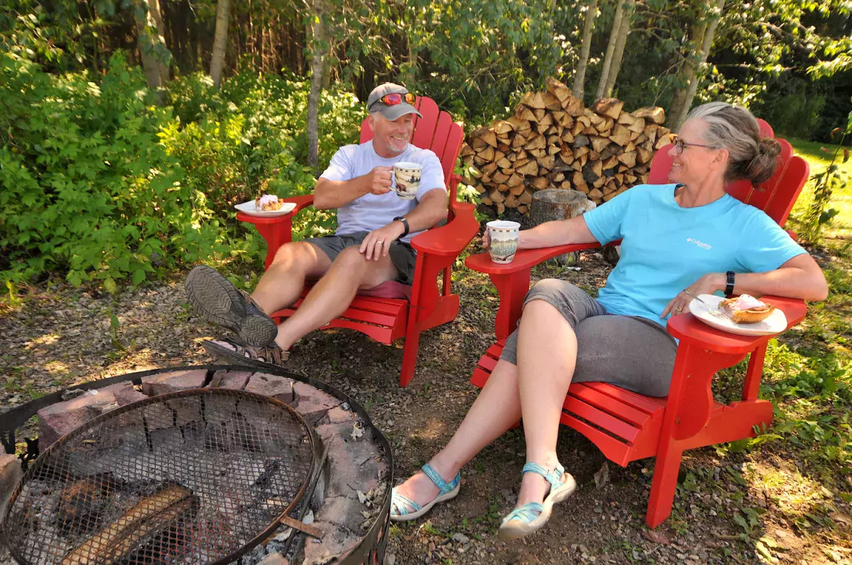 A couple sits by fire pit at Evergreen Birch Lodge in Lac La Biche